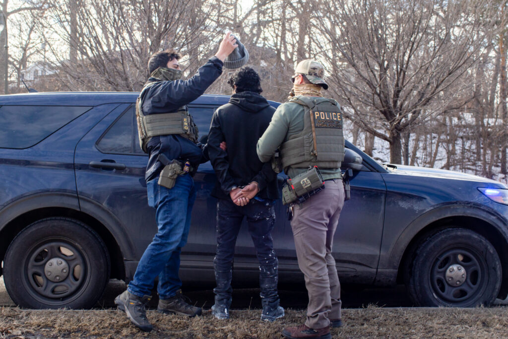 ICE agents search a passenger and arrest him and the driver during a traffic stop in Robbinsdale, Minnesota.